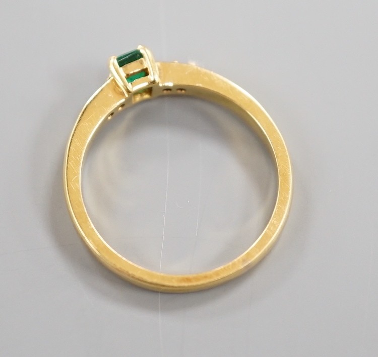 A modern 18ct gold and single stone emerald set ring, with four stone diamond set shoulders, size O, gross weight 3.4 grams
